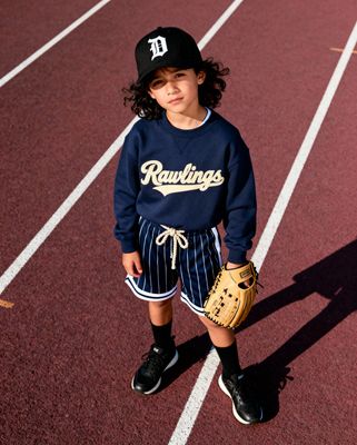 a young boy in a baseball uniform standing on a track