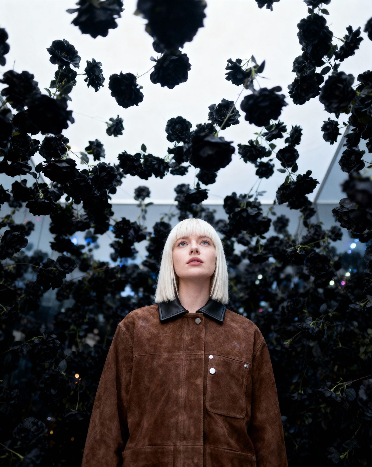 a woman standing in front of a bunch of black flowers