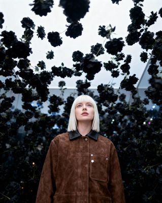 a woman standing in front of a bunch of black flowers