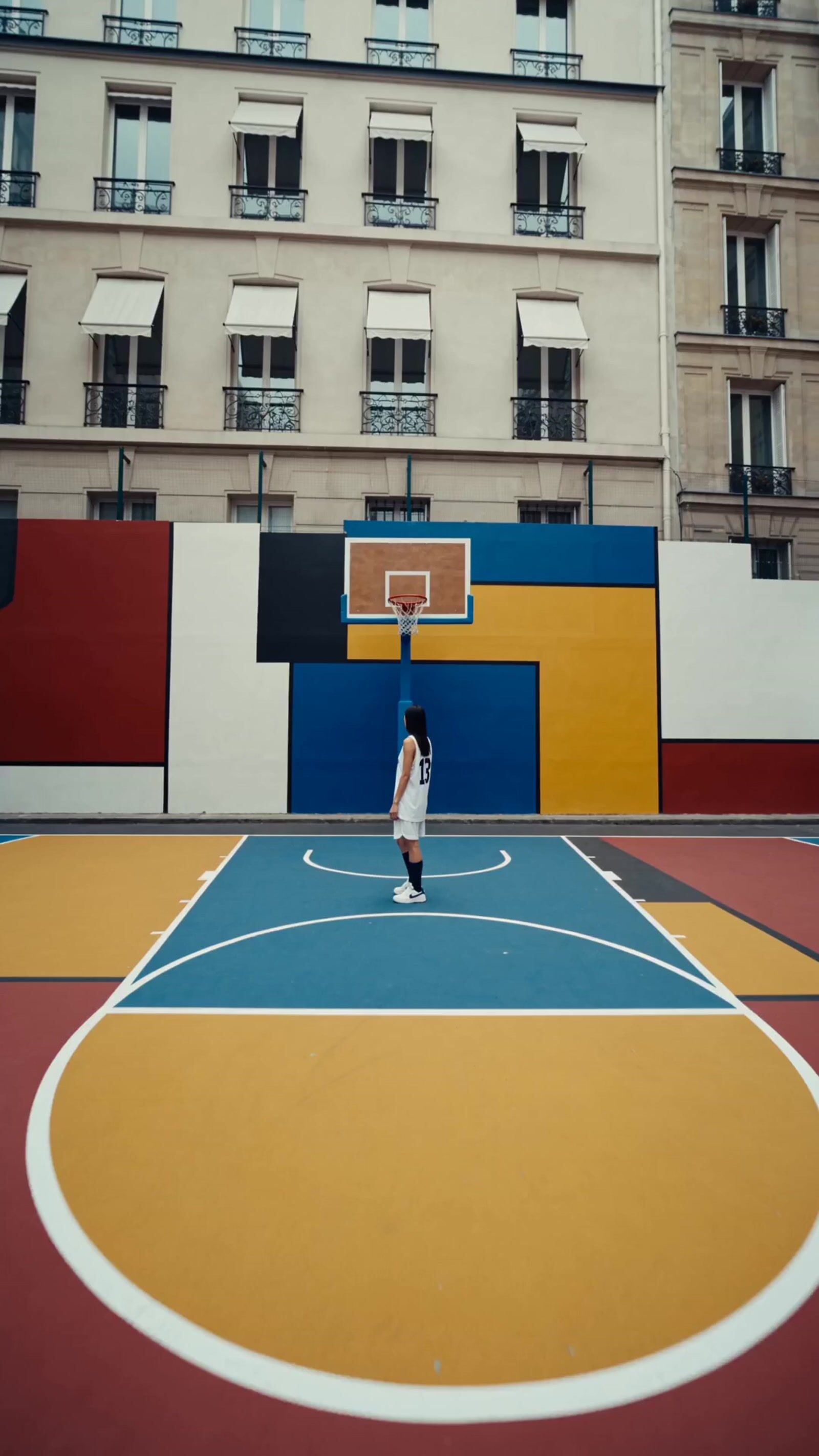 a person standing on a basketball court in front of a building