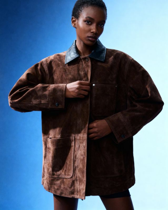 a woman in a brown jacket is posing for a picture