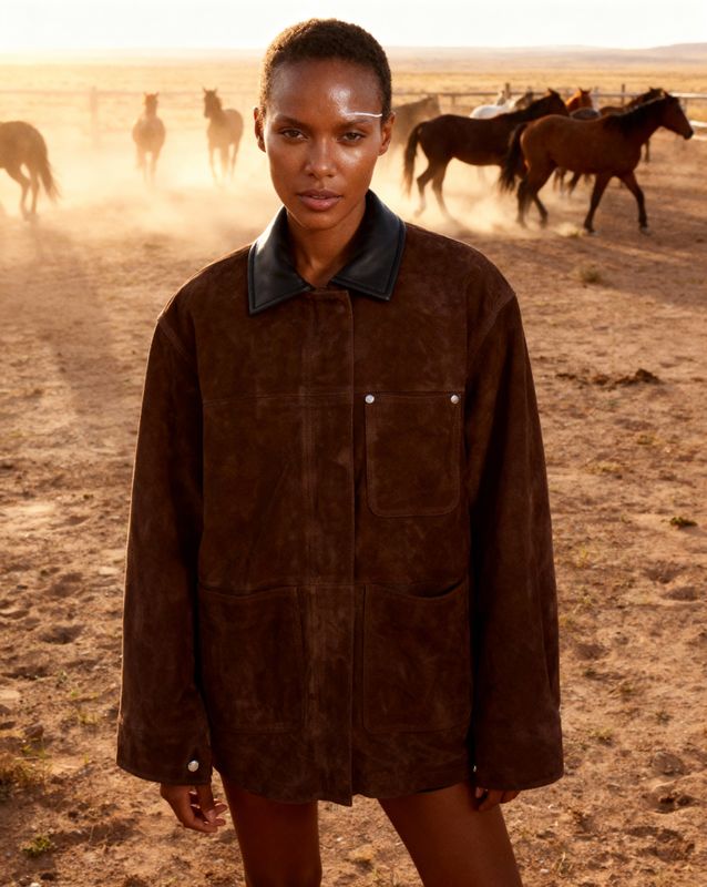 a woman standing in front of a herd of horses