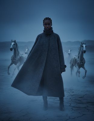a woman standing in front of a group of horses