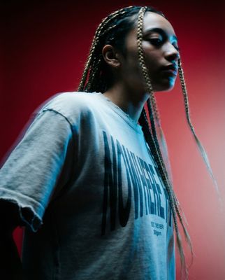 a woman with braids standing in front of a red background