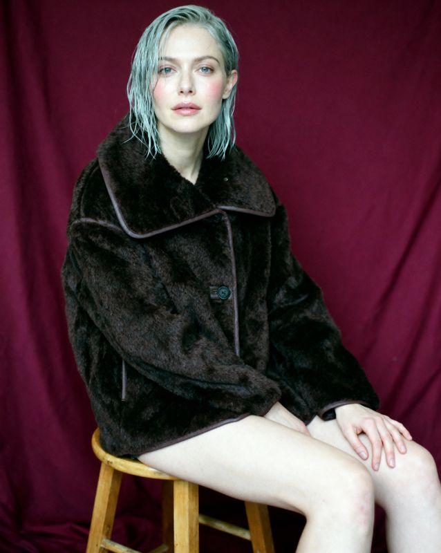 a woman with blue hair sitting on a stool