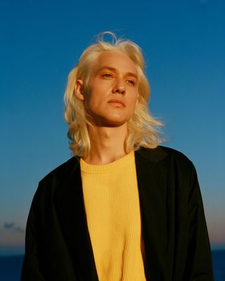 a woman with blonde hair standing in front of the ocean
