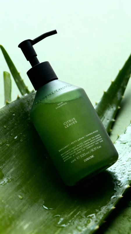 a bottle of green liquid sitting on top of a leaf