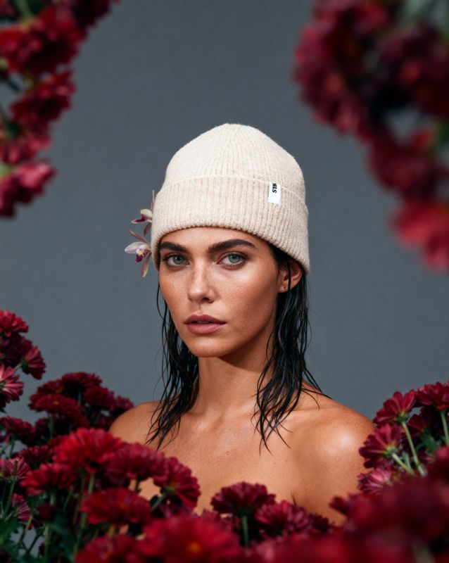 a woman wearing a white beanie with flowers around her