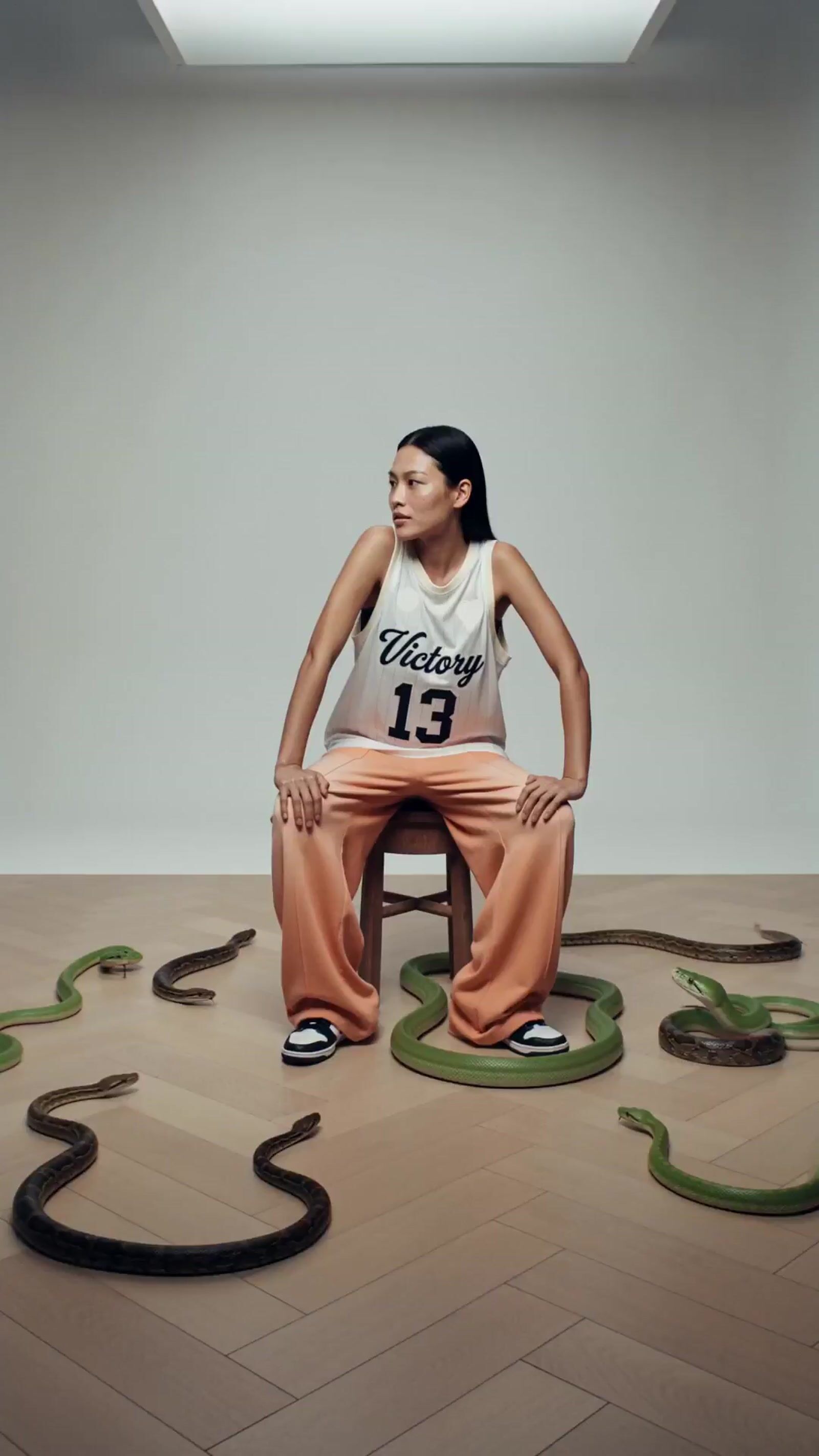 a woman sitting on top of a chair surrounded by snakes