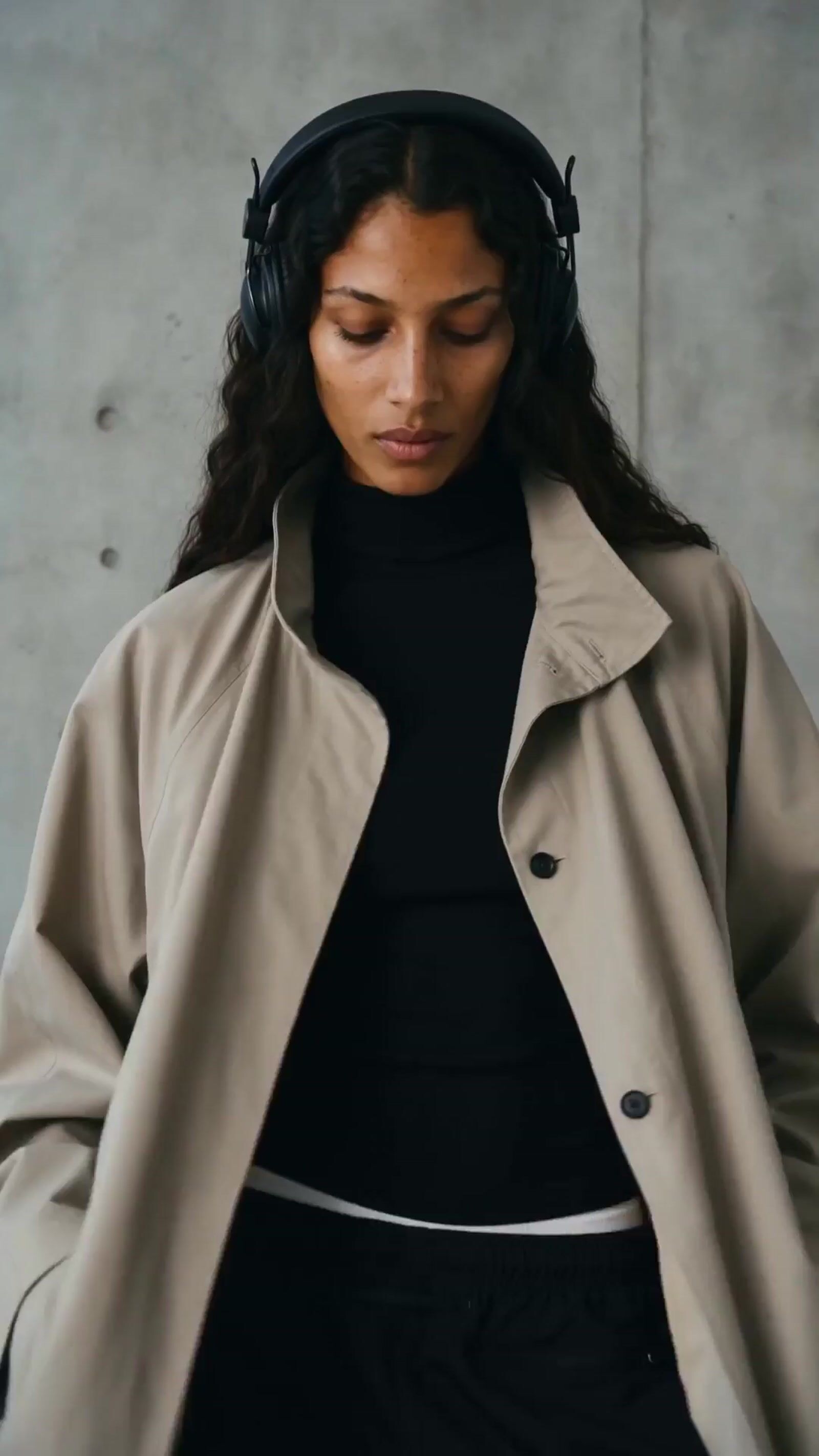 a woman wearing headphones and a trench coat