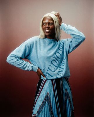 a woman in a blue shirt and pleated skirt