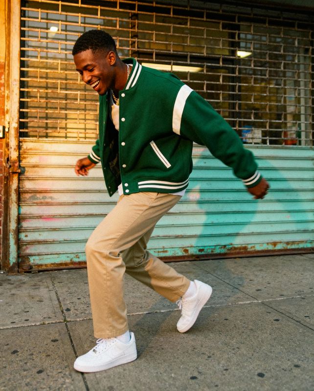 a man in a green jacket is walking down the street