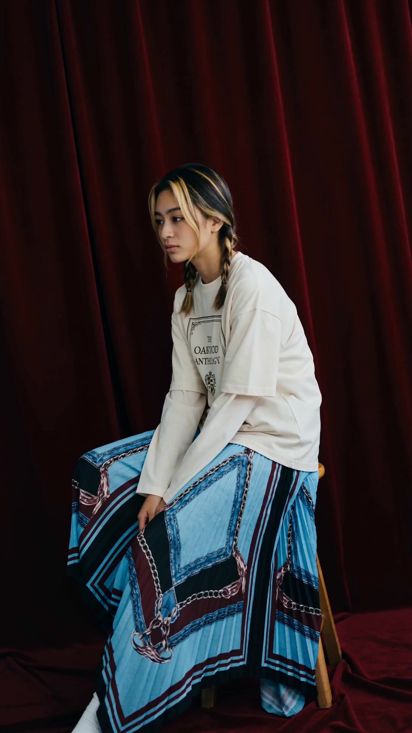 a woman sitting on a chair in front of a red curtain