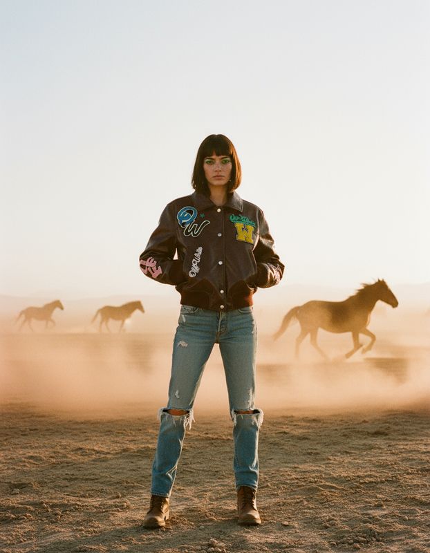 a woman standing in front of a herd of horses