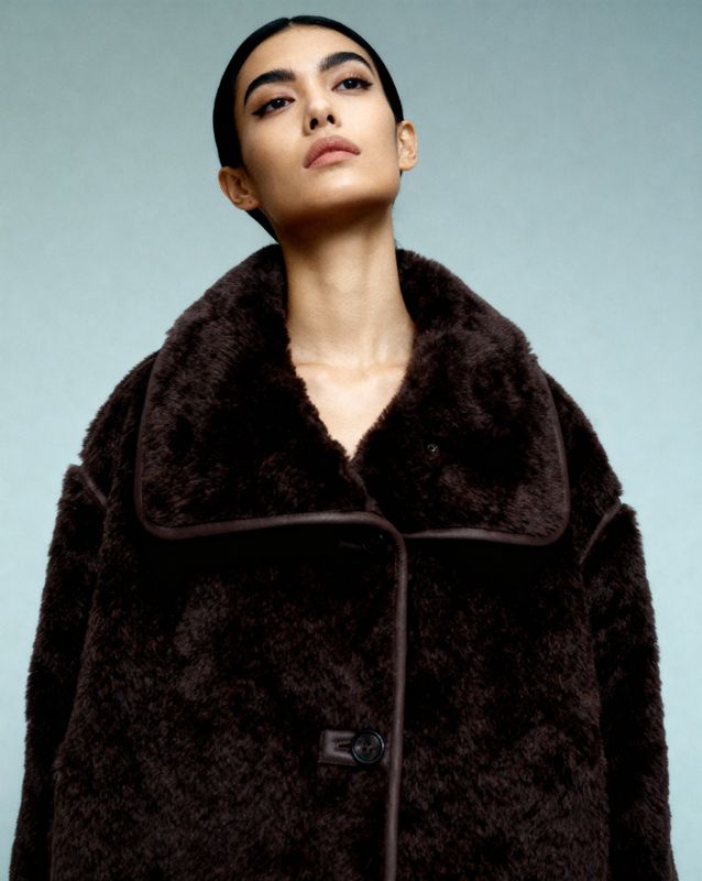 a woman wearing a black coat with a fur collar