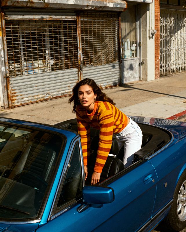 a woman leaning out the window of a blue car