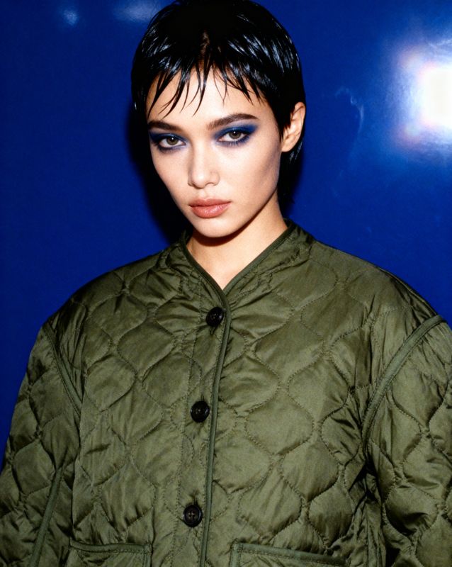 a woman in a green jacket with blue eyes