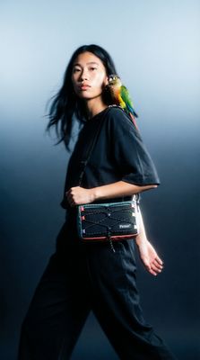 a woman holding a bird on her shoulder