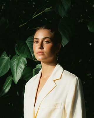 a woman standing in front of a green plant