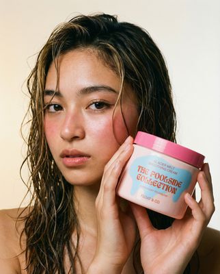 a woman with wet hair holding a jar of cream