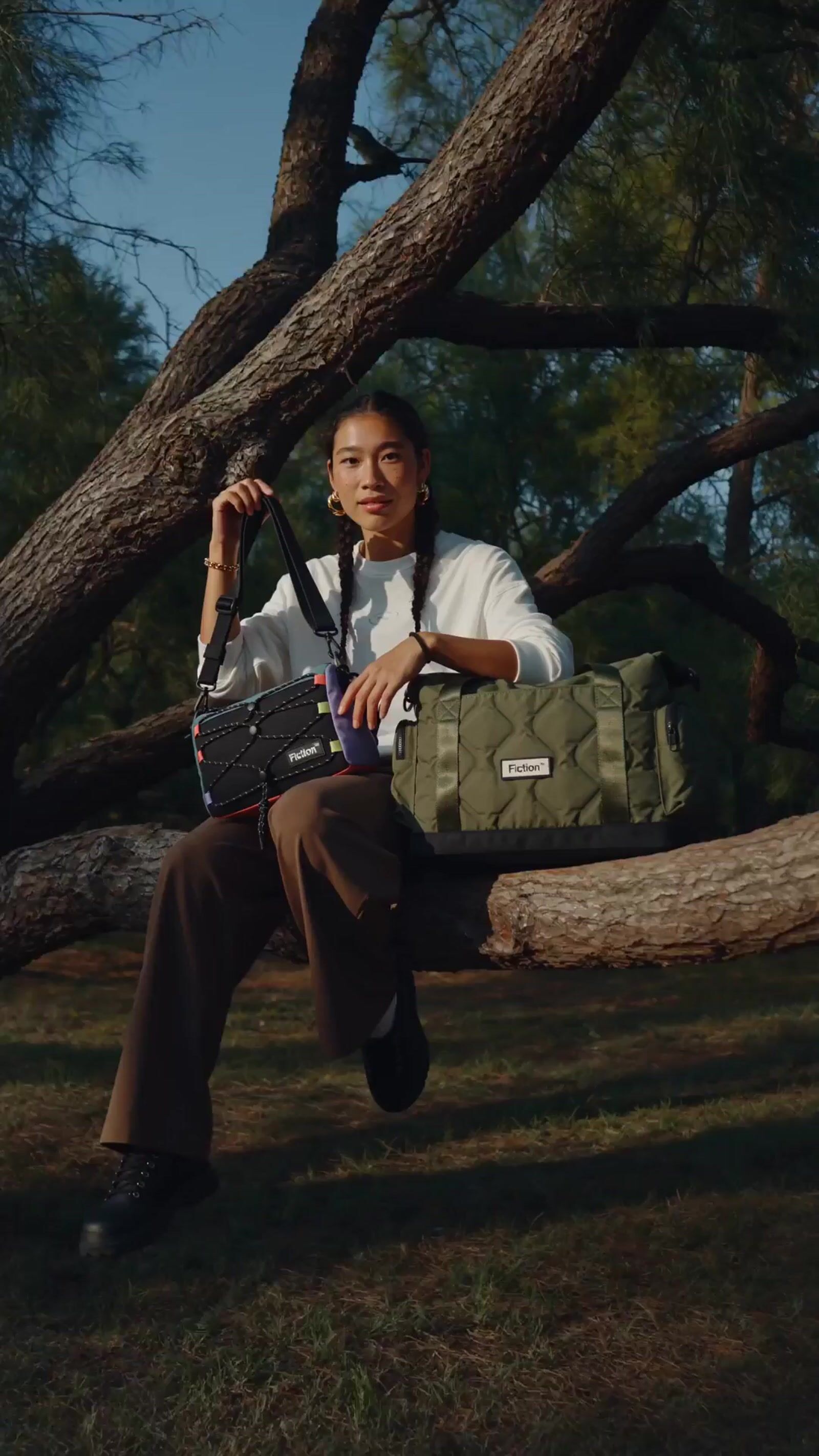 a woman sitting on a tree branch holding a camera