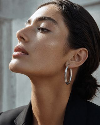 a woman wearing a black suit and large hoop earrings