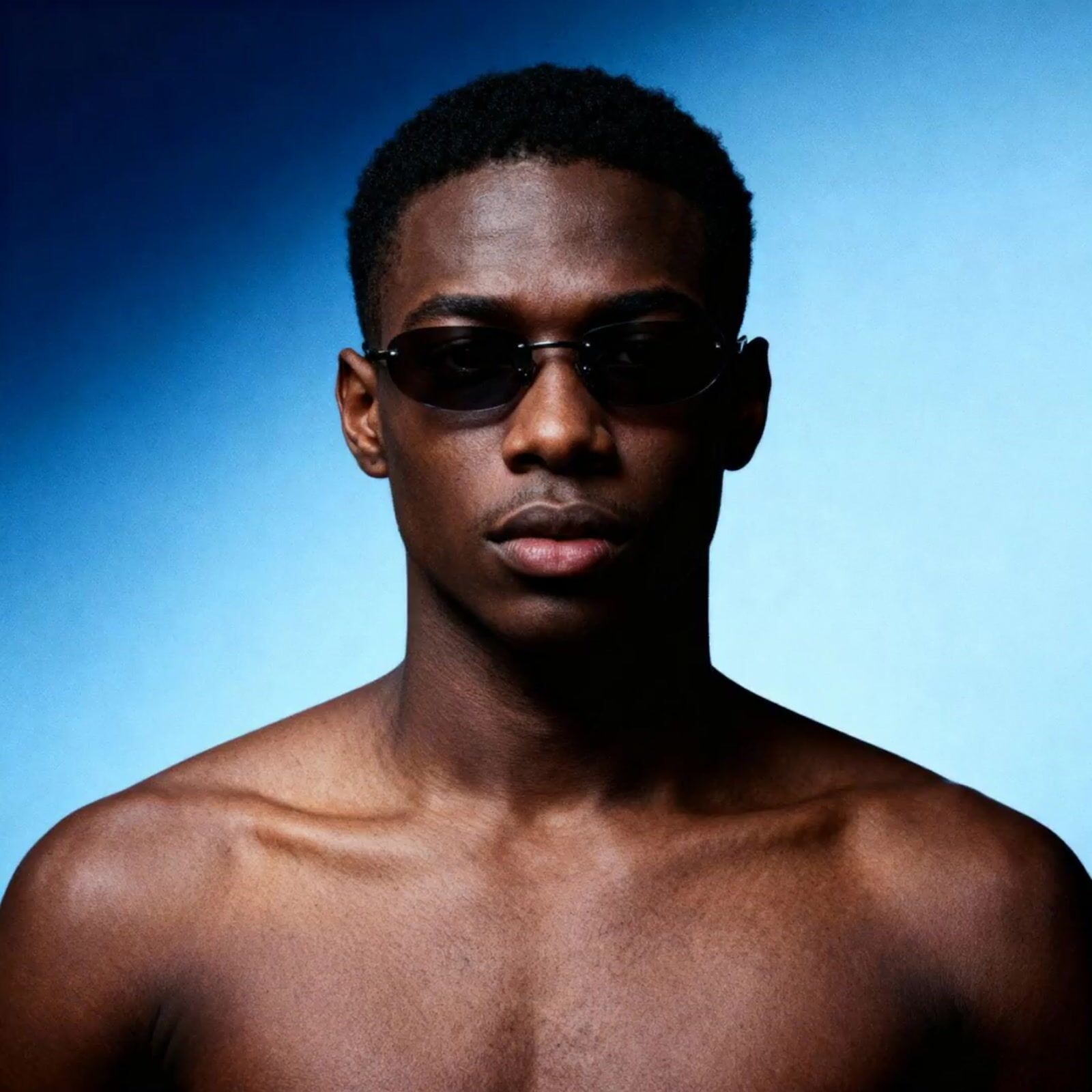 a man with no shirt wearing sunglasses on a blue background