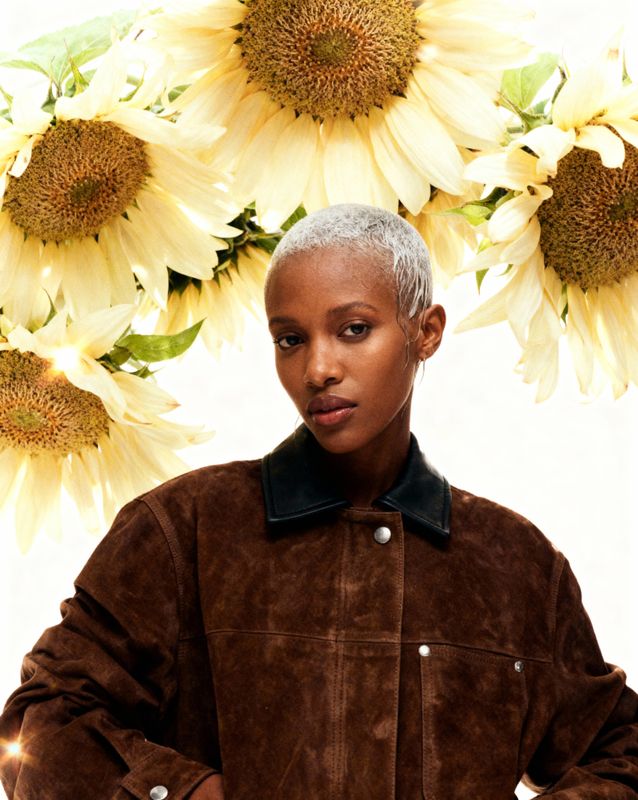 a woman standing in front of a bunch of sunflowers