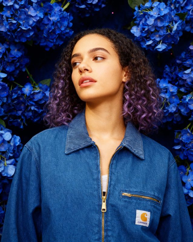 a woman standing in front of blue flowers