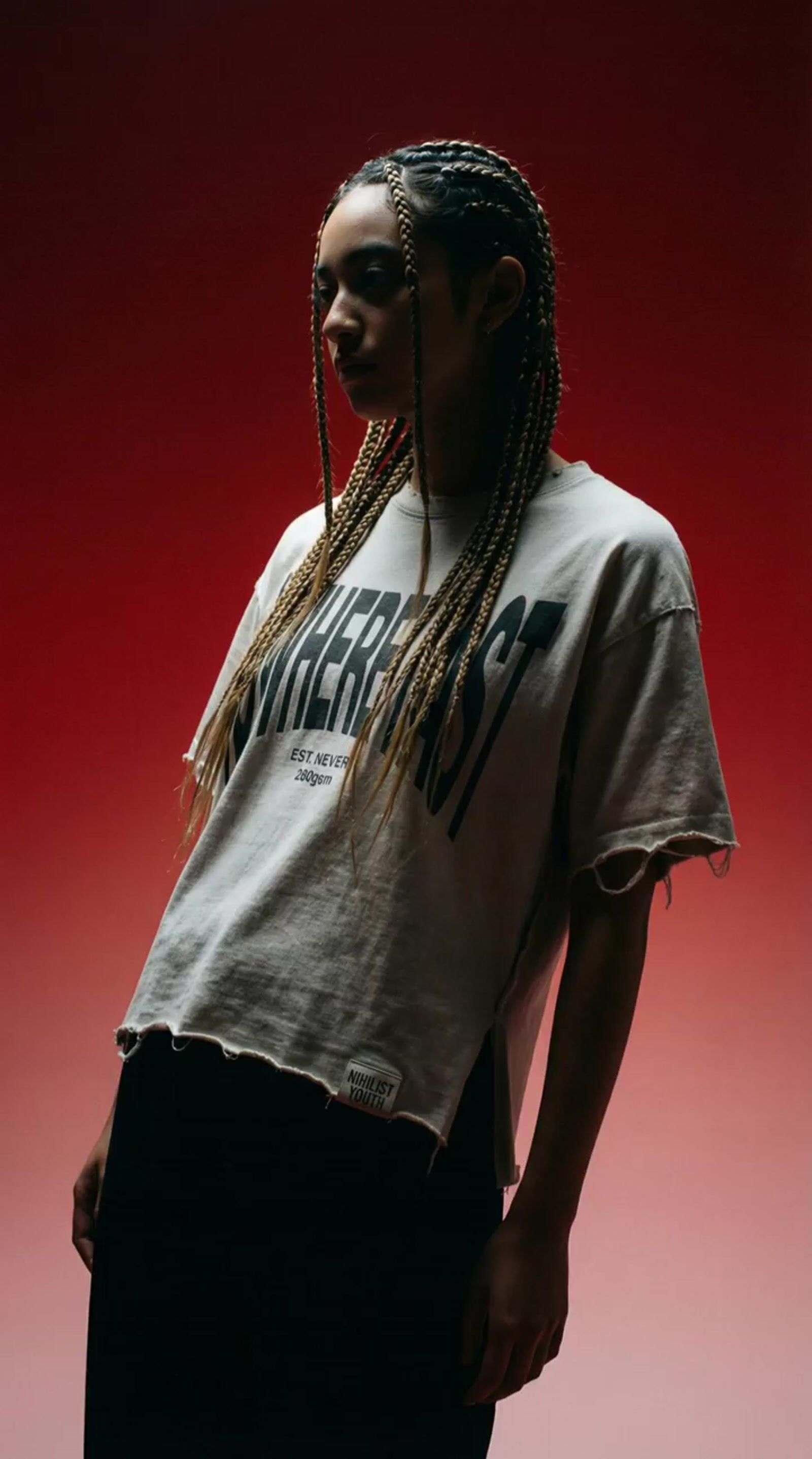 a man with dreadlocks standing in front of a red background