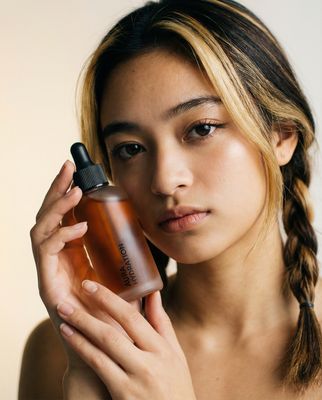 a woman holding a bottle of perfume in front of her face