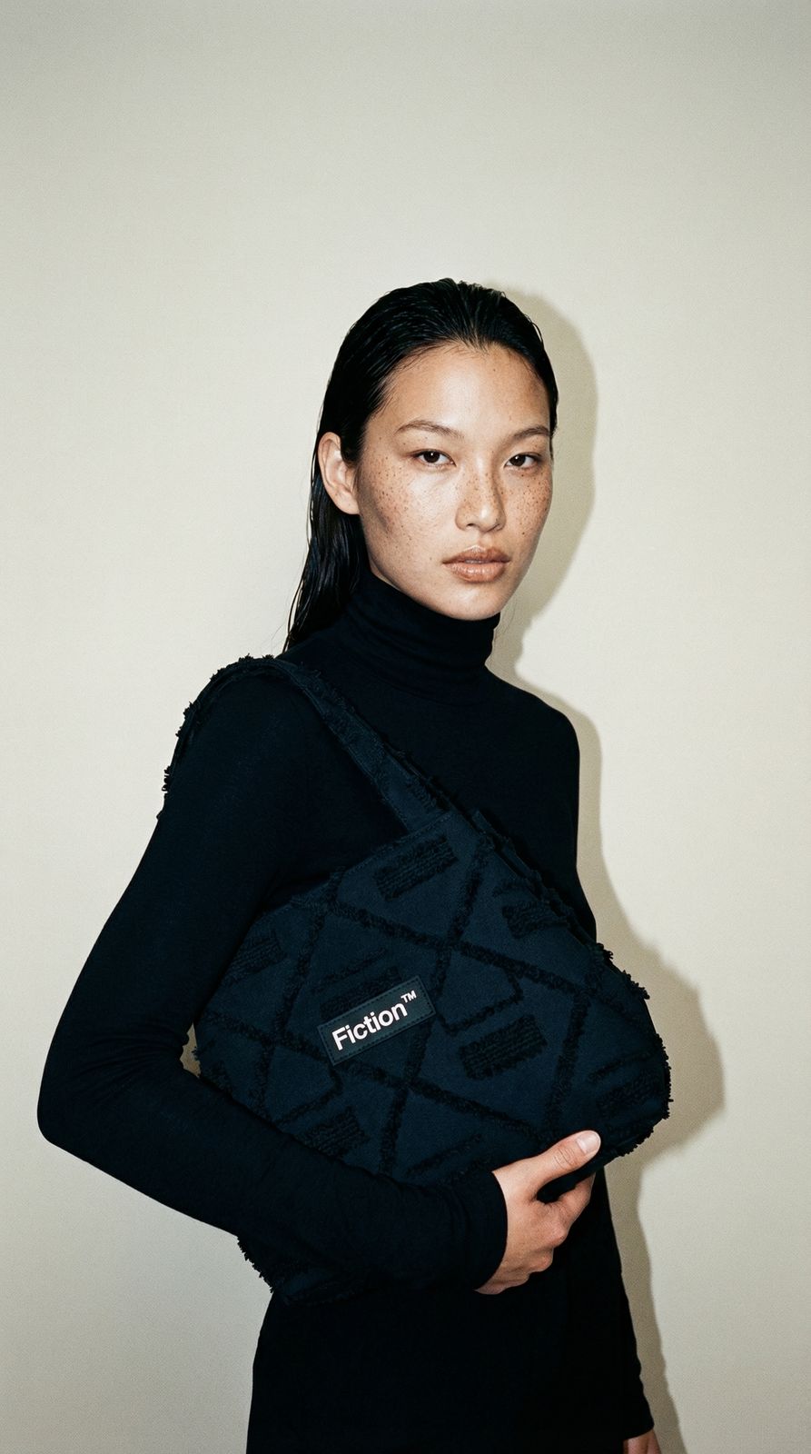 a woman in a black top is holding a black bag
