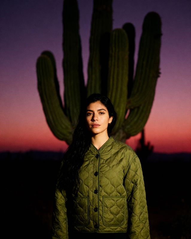 a woman standing in front of a cactus