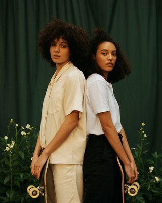 two women standing next to each other holding skateboards