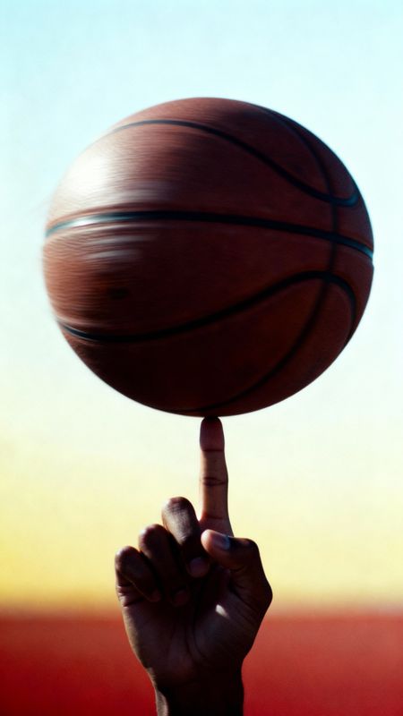 a hand holding a basketball up to the sky
