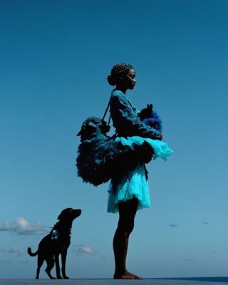 a woman standing next to a dog on a beach