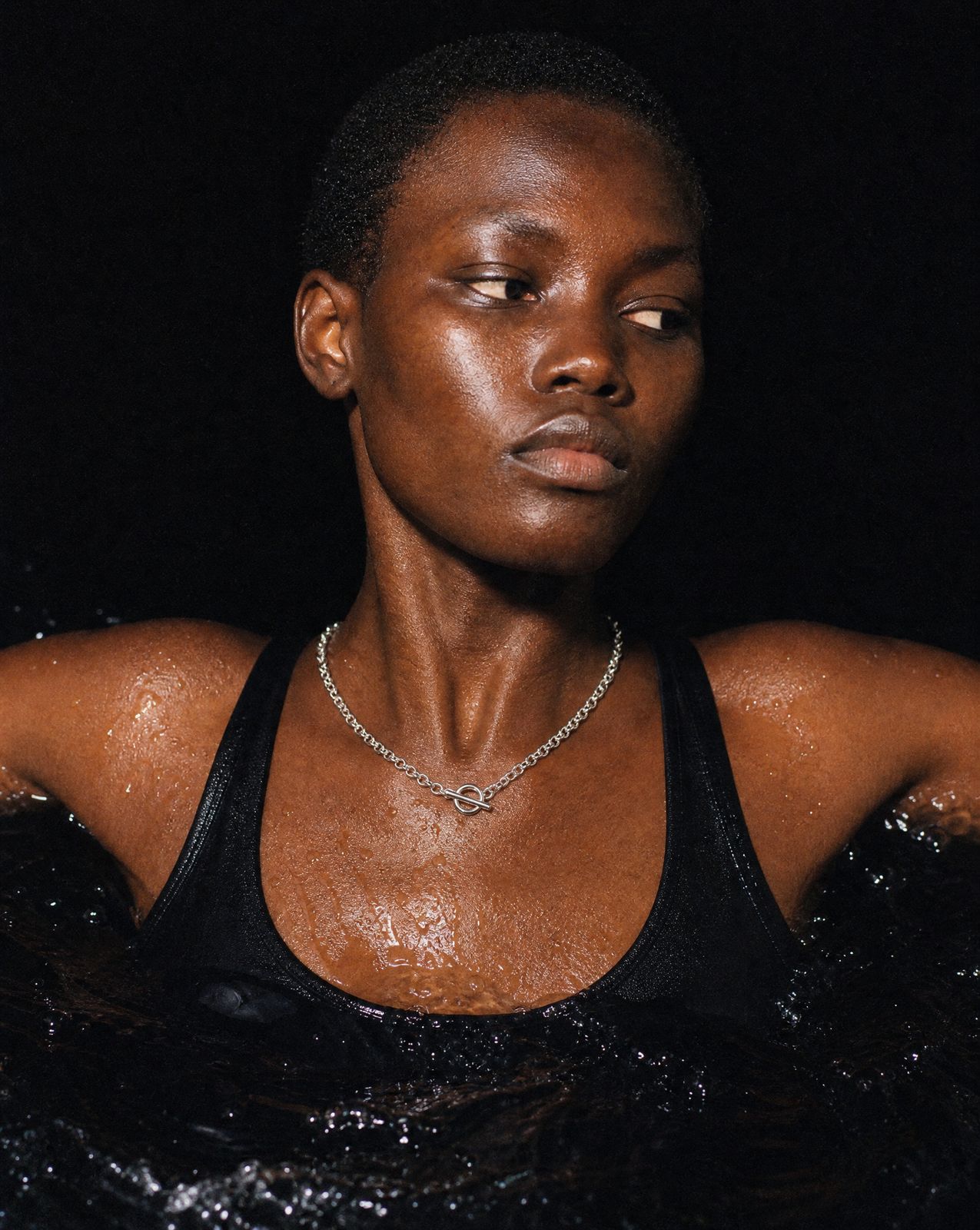 a woman in a black tank top with a diamond necklace