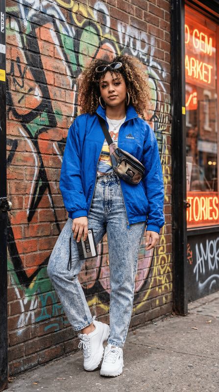 a woman standing in front of a graffiti covered wall
