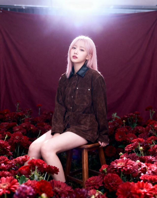 a woman sitting on a stool in a field of flowers