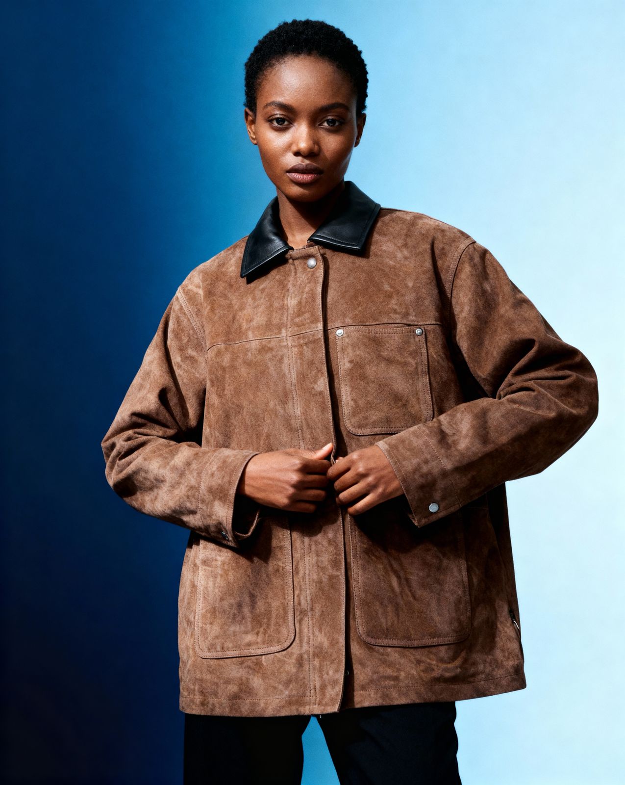 a woman wearing a brown jacket and black pants