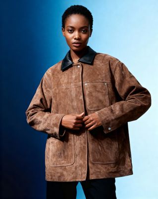 a woman wearing a brown jacket and black pants