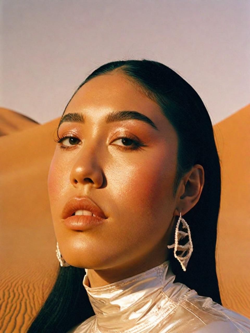 a woman in a white shirt and earrings in the desert