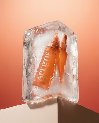 an orange beverage in an ice block on a pink background