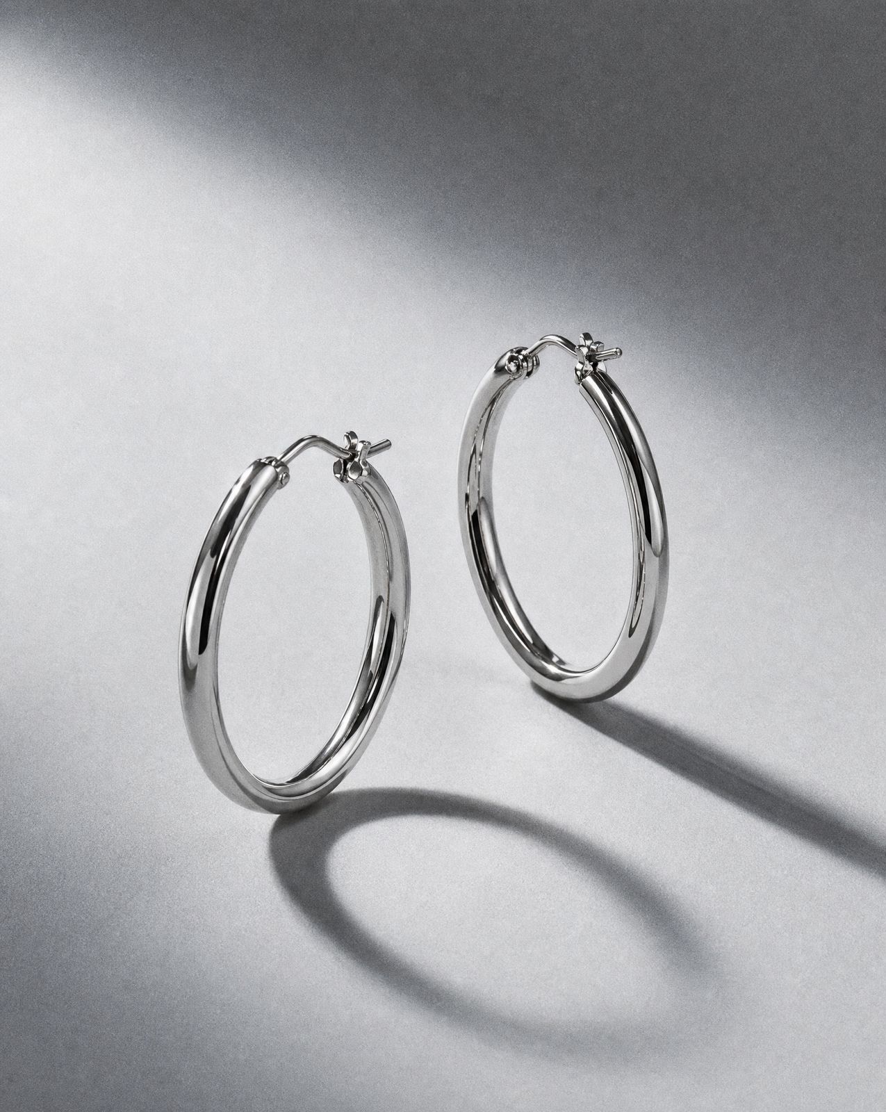 a pair of silver hoop earrings on a white background