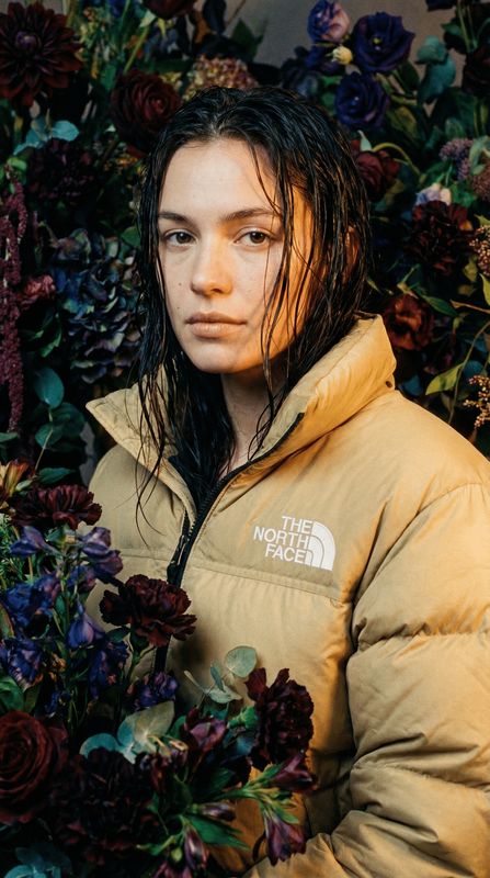 a woman standing in front of a bunch of flowers