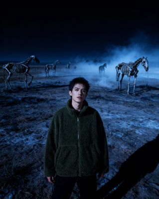 a man standing in front of a group of zebras