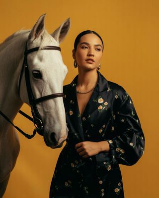 a woman standing next to a white horse