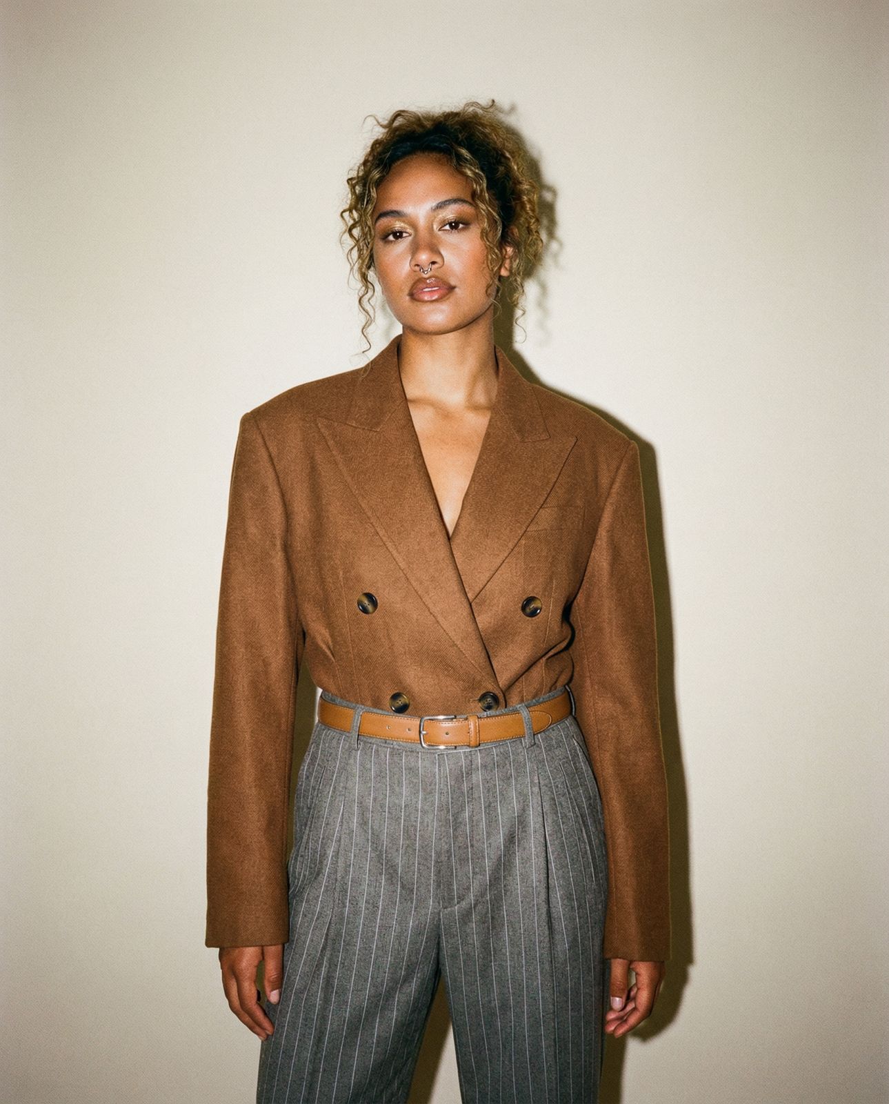 a woman standing in front of a white wall