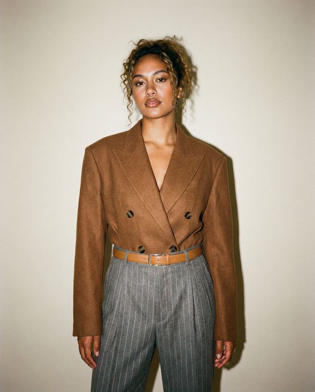 a woman standing in front of a white wall