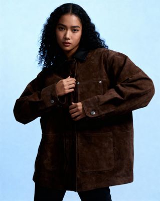 a woman wearing a brown jacket and black pants